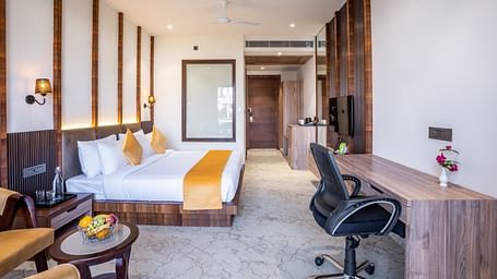 A bedroom with a large bed, a coffee table, a work desk and a revolving chair - Shervani Pebbles & Pines, Corbett