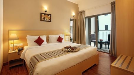 A double bed with side tables and lamps inside Deluxe Room - Starlit Suites, Kochi