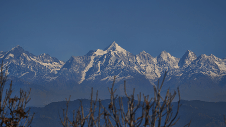 Sunlit Himalayan mountains visible from afar under a clear blue sky