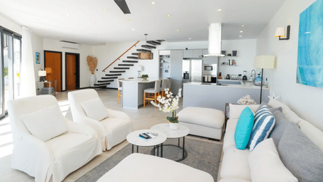 Airy living room with white sofas, ceiling fan, and large windows at Tamarind Hills Resort and Villas - Antigua.