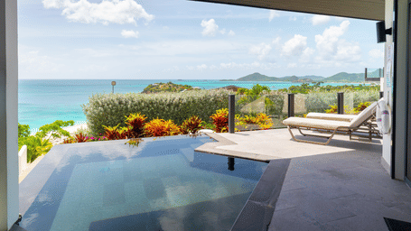 Seastar Suite at Tamarind Hills Resort and Villas, Antigua, featuring an outdoor terrace with pool, lounge chairs at poolside, and a scenic view