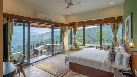 Spacious room with a large bed and a large glass sliding door leading to a balcony with a mountain view at The Chamomile Estate.