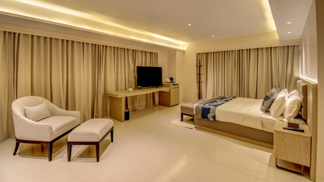 The Deluxe King Room with two beds, a television, and a desk, bright interior lighting - The SSK Solitaire Boutique Hotel & Spa, Gangapur Road - Nashik