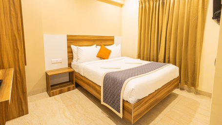 A minimalist bedroom with a double bed, bedside table, and gold-coloured curtains - Urban Comforts