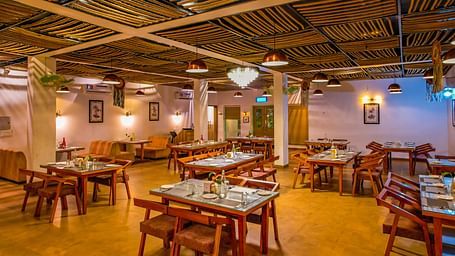 Another view of the dining hall at Vedikant Resorts The Mallard Corbett reveals more tables and chairs in a well-lit setting.