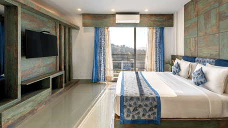 A bedroom with a neatly arranged bed and a tv mounted on the wall - Via Lakhela Resort & Spa