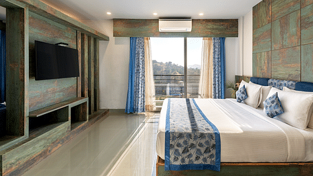 A bedroom with a neatly arranged bed and a tv mounted on the wall - Via Lakhela Resort & Spa
