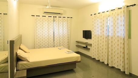A room at Wyt Hotels Transit Nest, Madurai featuring a double bed, curtains covering windows, and a flat TV screen.
