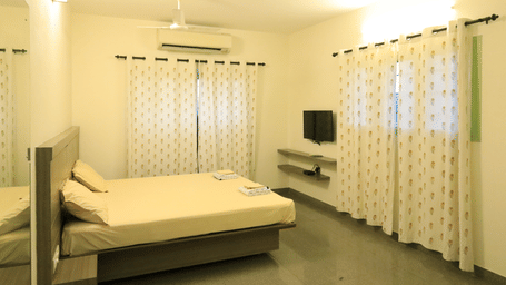 A room at Wyt Hotels Transit Nest, Madurai featuring a double bed, curtains covering windows, and a flat TV screen.