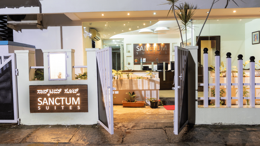Sanctum Suites Domlur Bangalore property entrance with signboard and decorative fencing