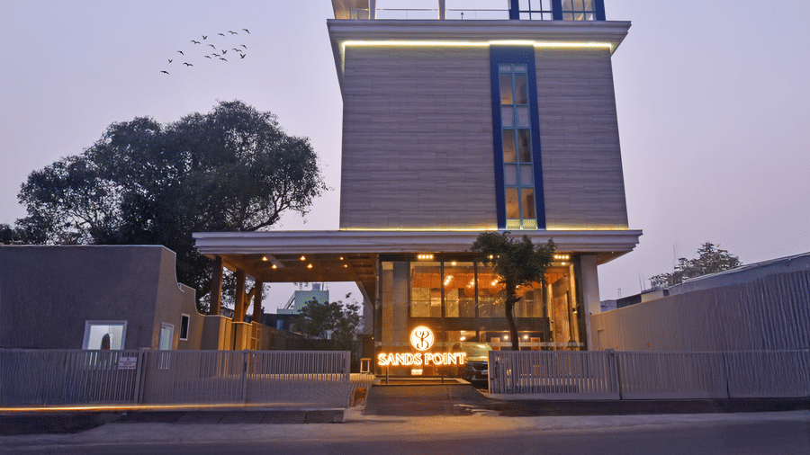 A wide view of the modern hotel exterior against a purple dusk sky at Sands Point Hotel, Pondicherry.