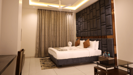 A large double bed sits below a decorative dark panelled wall with warm lighting - Lords Inn Sangam, Bhopal