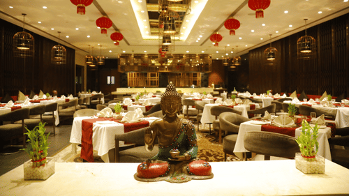 A dining space at Pride Plaza Hotel, New Delhi, with several chairs and tables arranged for dining.