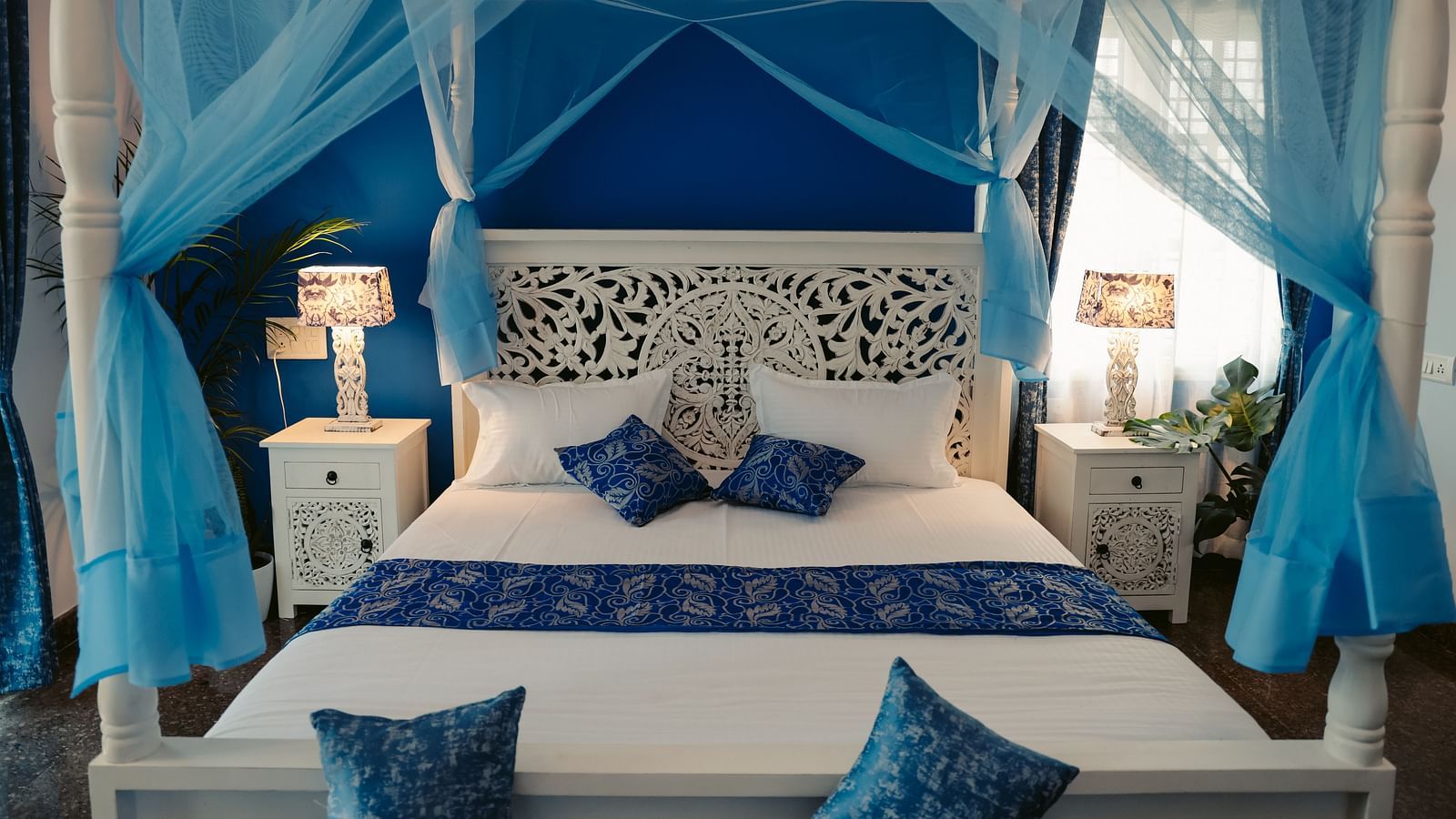 A bedroom with a white four-poster bed draped in sheer blue fabric | Adhyaya Heritage Reverbed