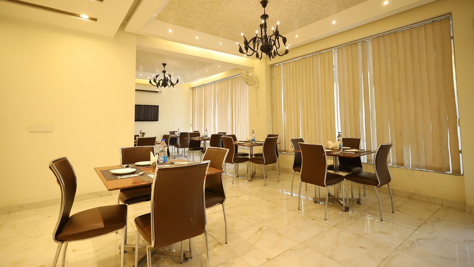 A brightly lit dining area features multiple tables and chairs - Asian Suites Cyber Park, Gurgaon