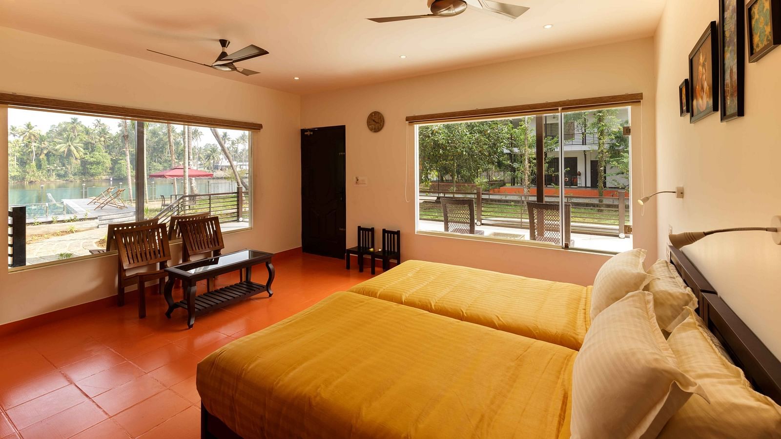 A bedroom with two beds, a seating area by a window, and ceiling fans.