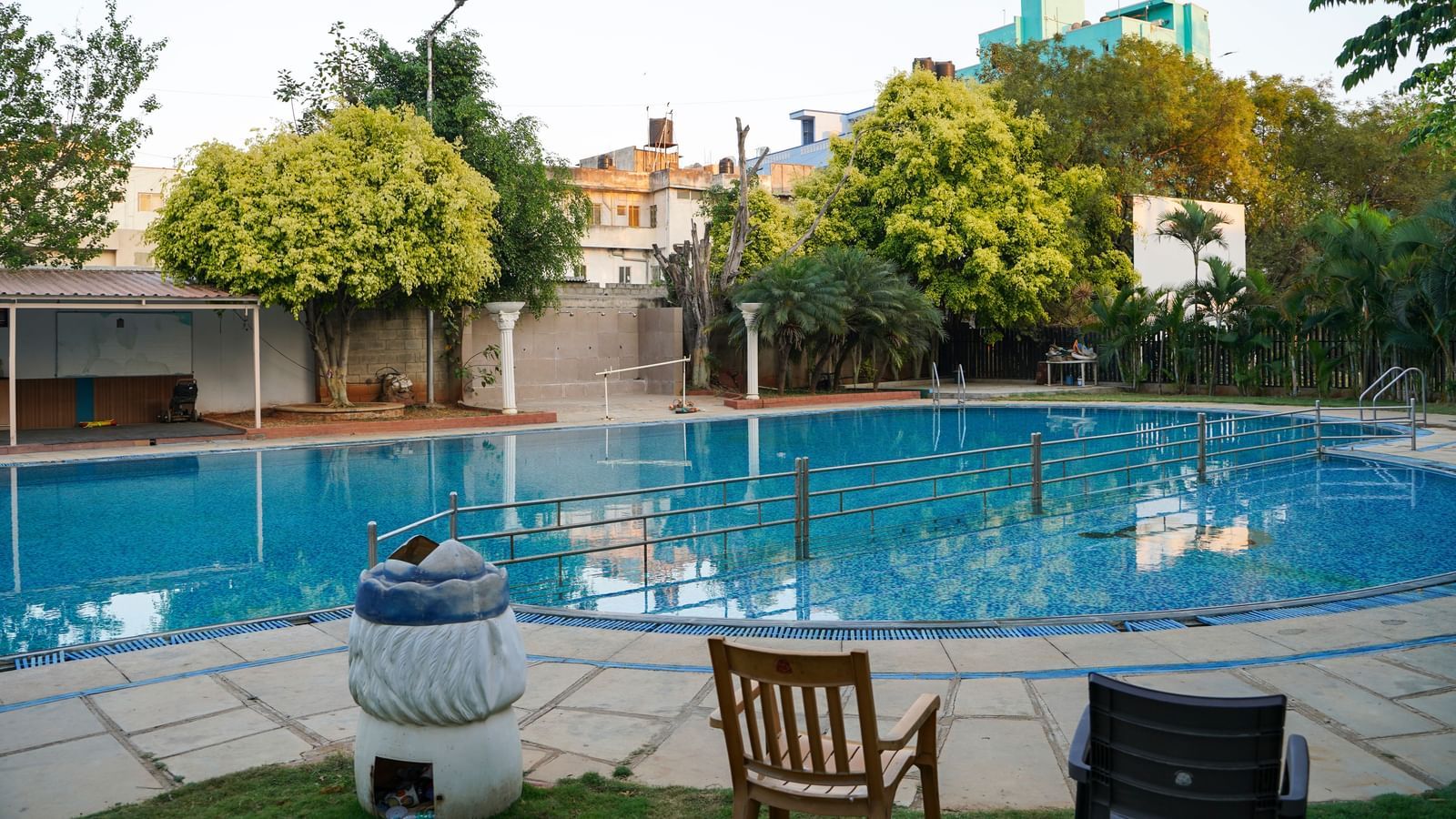 A sparkling outdoor swimming pool surrounded by greenery and lounge chairs at BNGV Grandeur Hotel and Banquets.