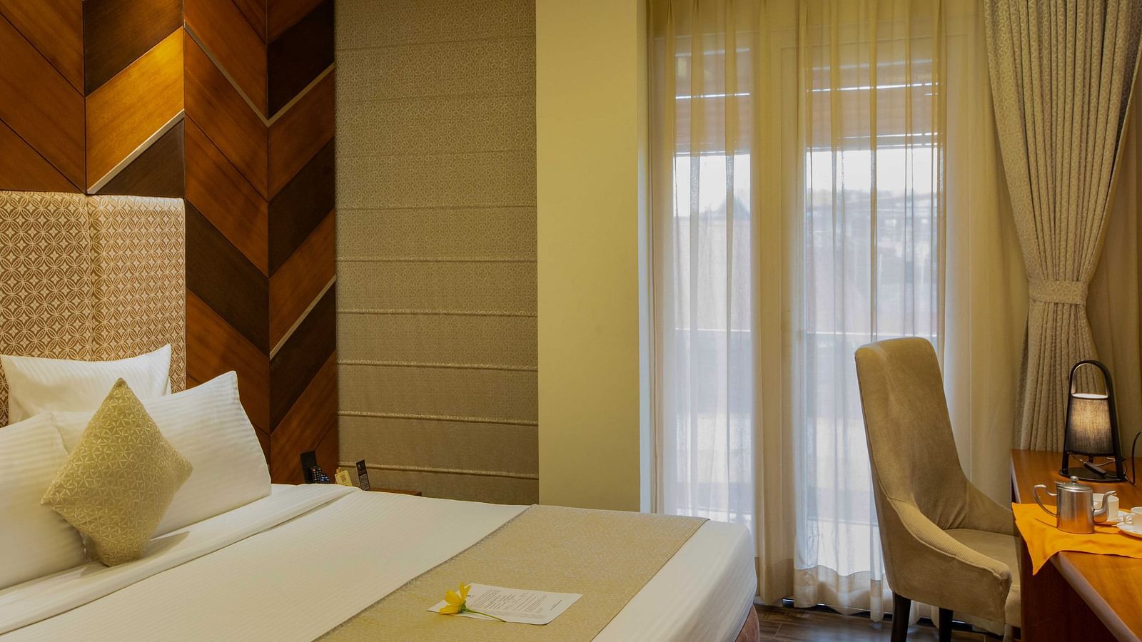 Image of Coral Suite at Coral Reef Hotel and Spa featuring a plush bed placed against a patterned wall next to the balcony door and a work desk near it