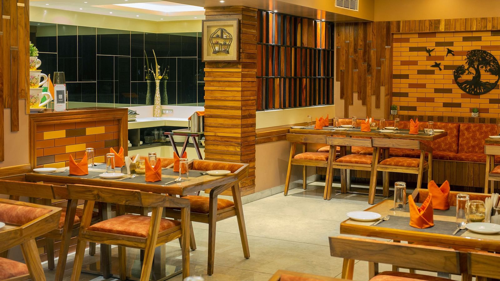 Image of the interiors of Honeycomb Restaurant at Coral Reef Hotel & Spa in Port Blair under warm lighting and walnut furniture 