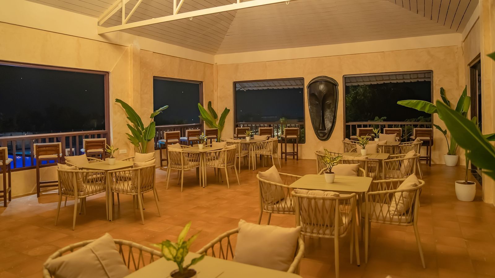 An interior of a restaurant with chairs and square tables arranged in sets - Crescent Resort, Goa
