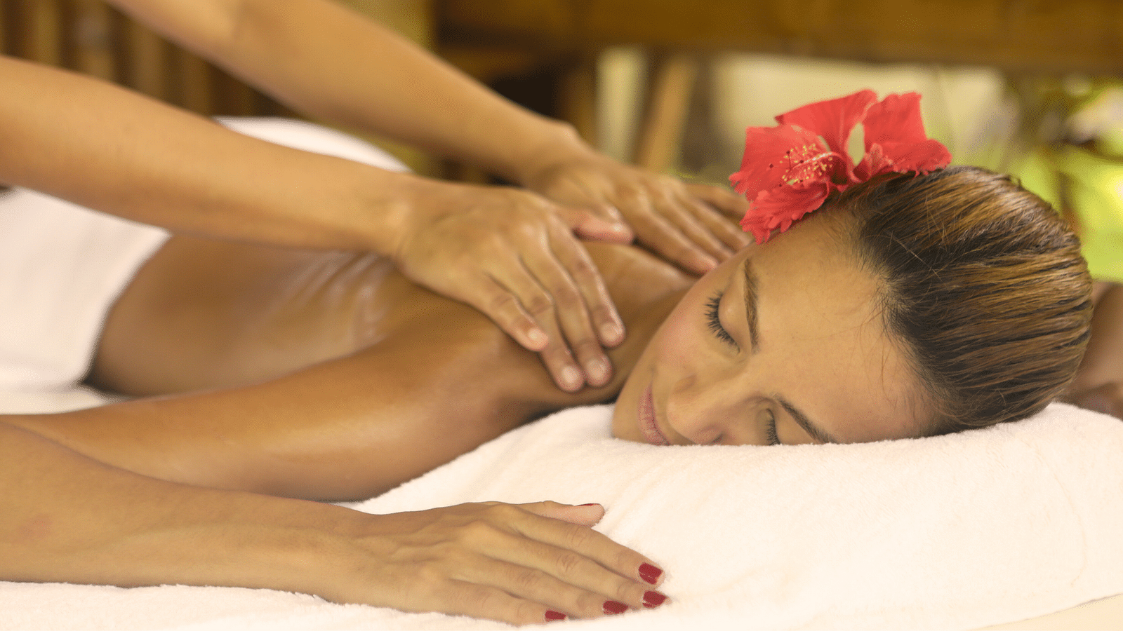 Spa therapist giving a relaxing massage to a woman with a flower in her hair at Flower Island Resort.