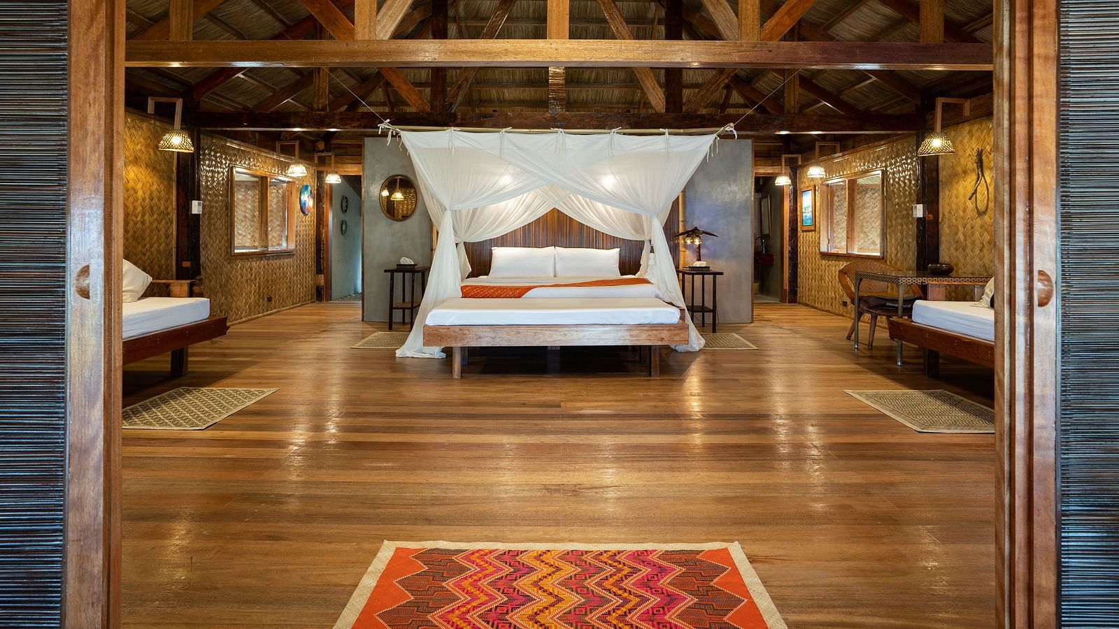 Interior of a room at Flower Island Resort with a canopy bed, wooden ceiling, and side lamps.