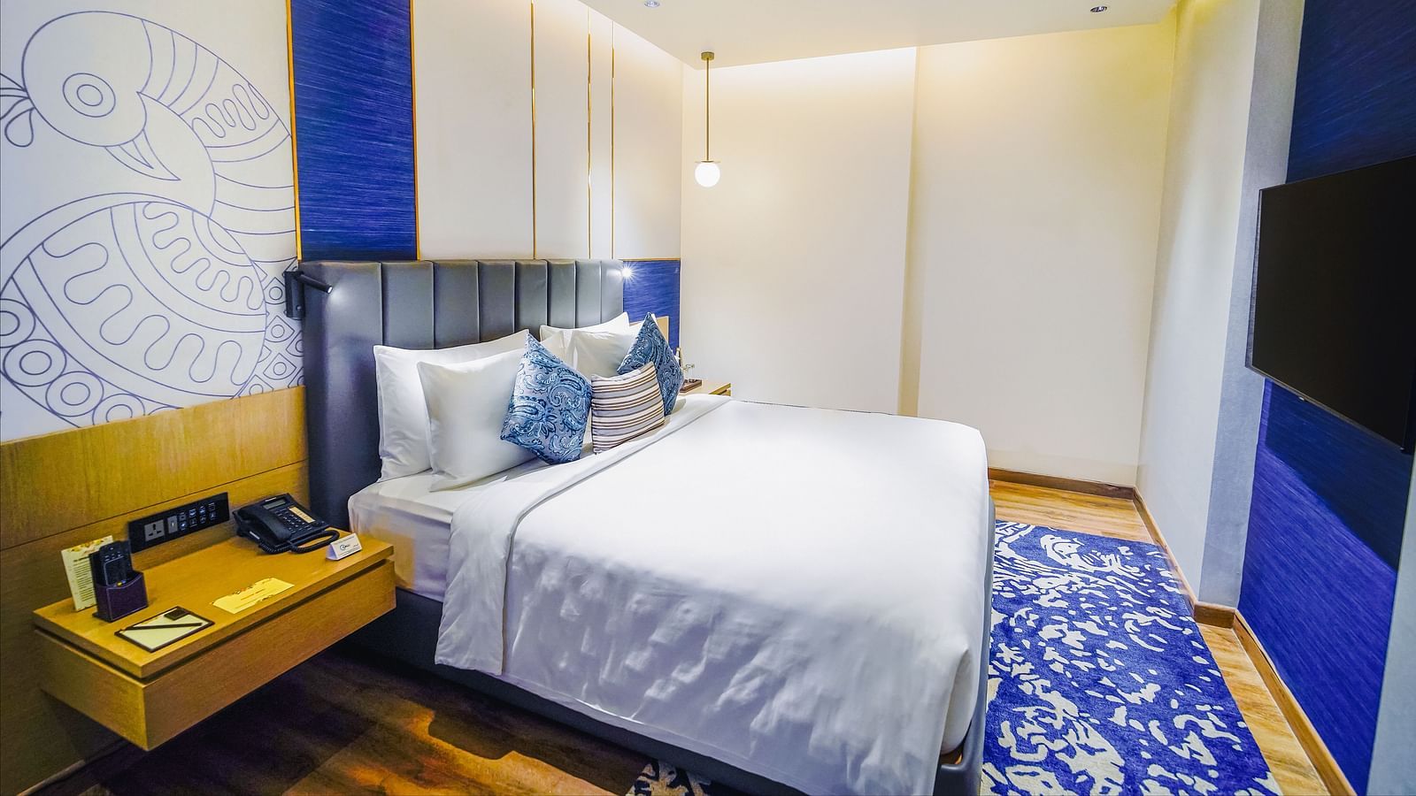 A Junior Suite in Madurai with a night stand placed beside a plush bed - Grand Madurai by GRT Hotels