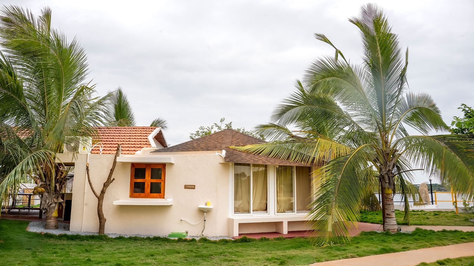 Image of a villa amidst a lawn and palm trees