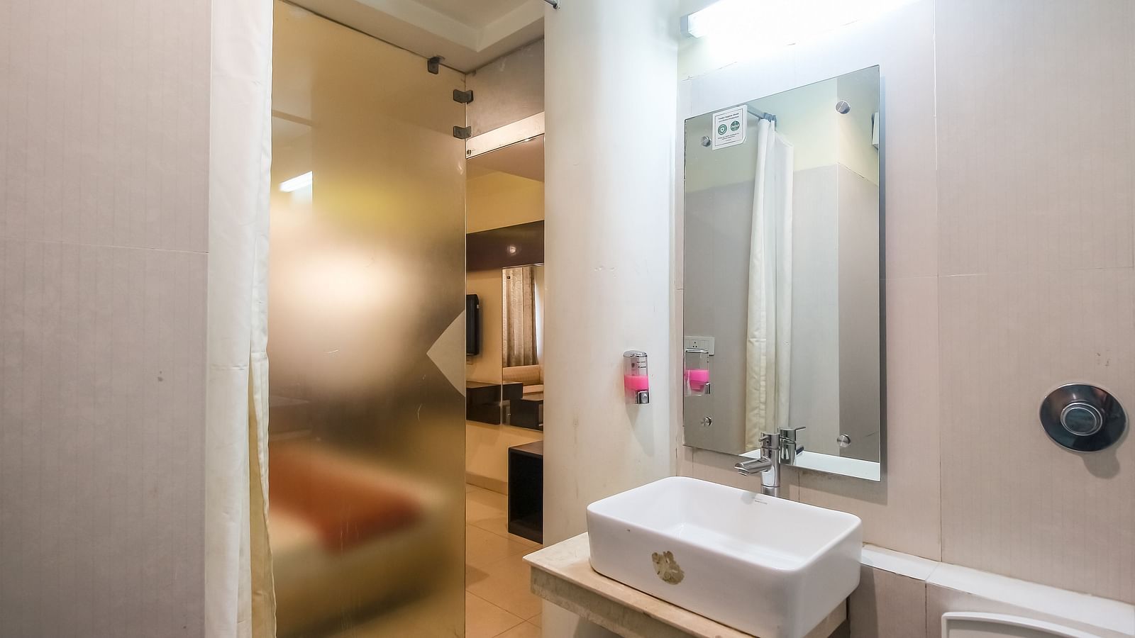 Bathroom with a sleek sink, a mirror, and a glass door - Hotel Diamond Plaza, Chandigarh.