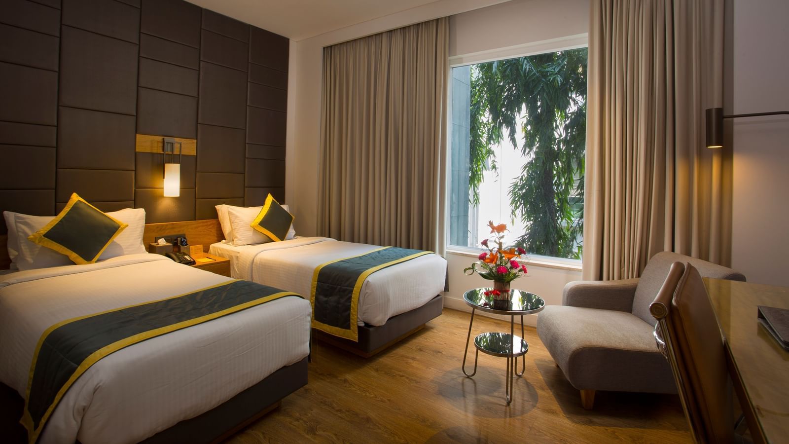 a bedroom with the curtains drawn out offering views of the city with two single beds and a sofa  - Hotel Fountain Tree By TGI - JP Nagar, Bangalore