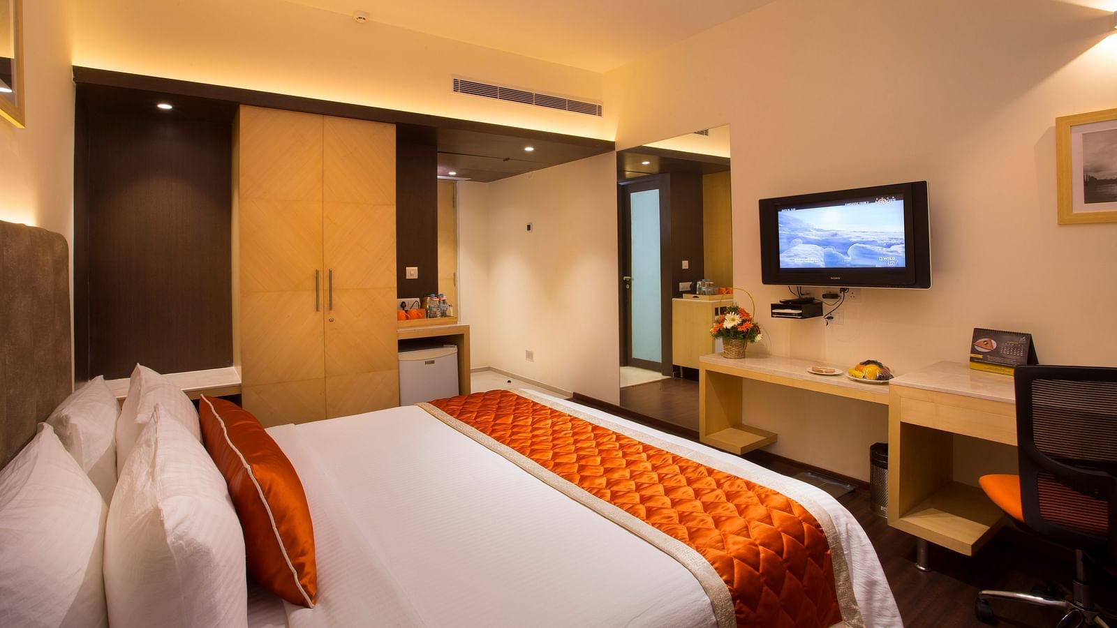 A comfortable hotel room with modern amenities, a large bed, a TV and a work desk with a chair - Hotel Langford Keys by TGI, Shanti Nagar