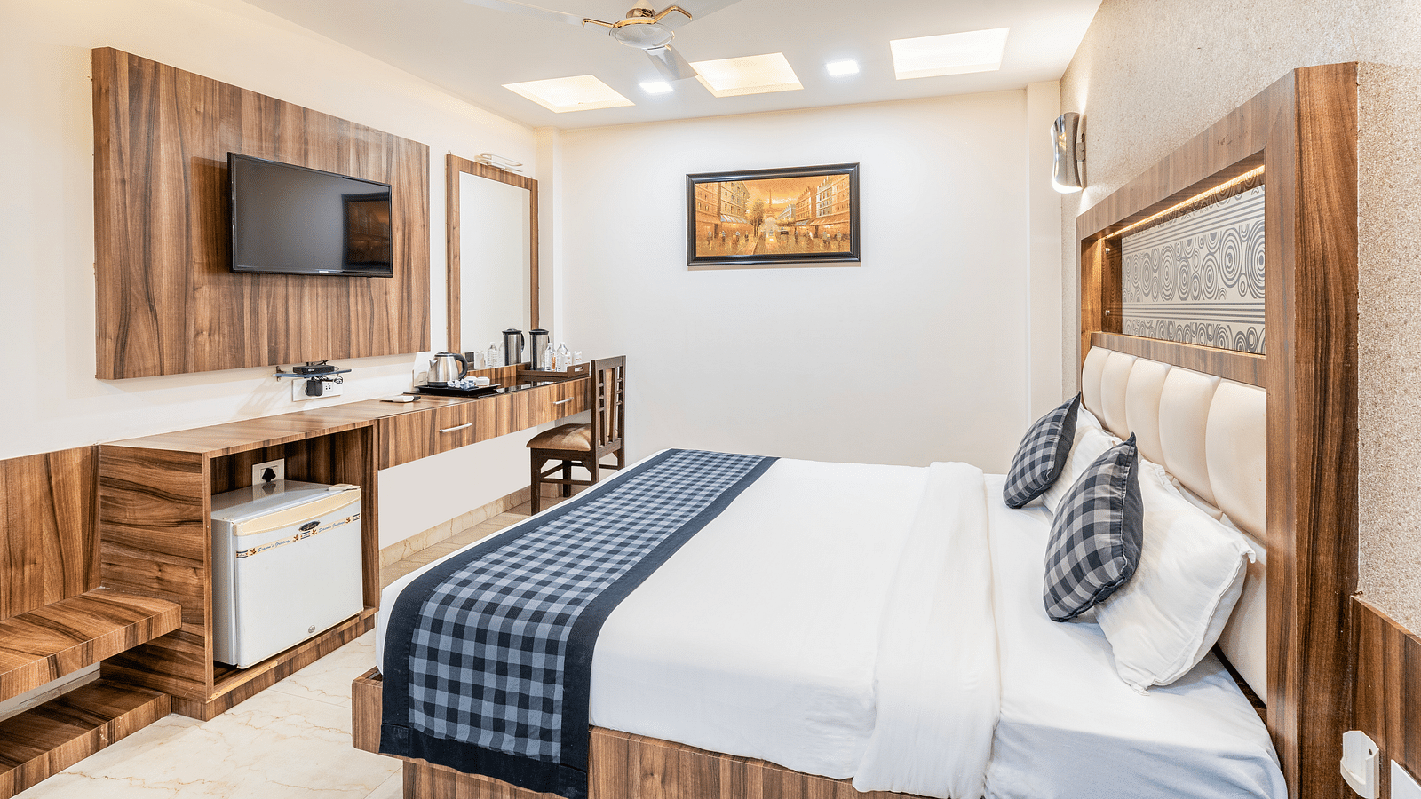 A cozy room at Hotel Moti Palace featuring a comfy bed, a flat-screen TV, and a dressing table.