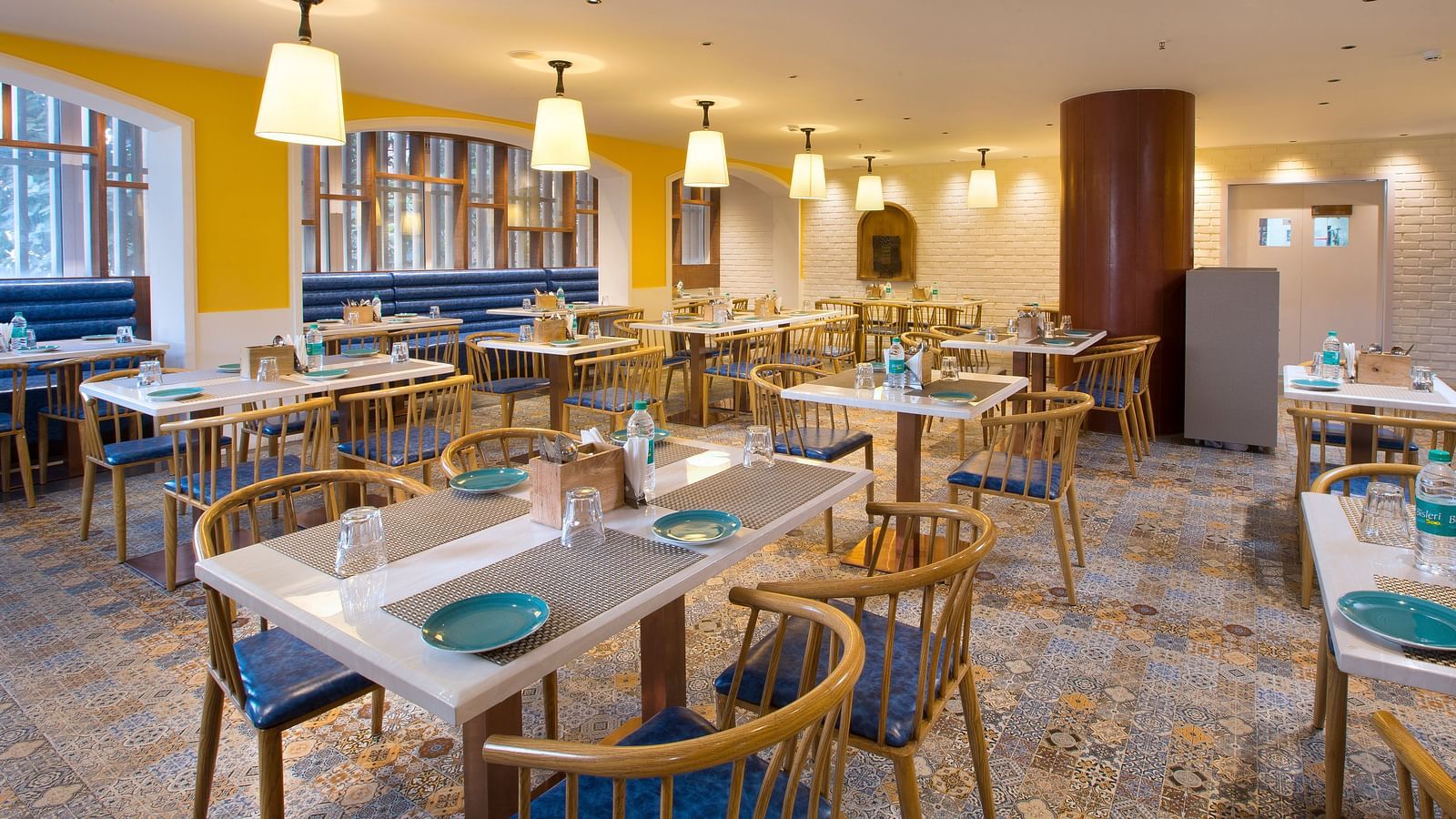 A spacious and brightly lit restaurant with wooden chairs, patterned tile floor and large windows - Hotel Southend by TGI - Bommasandra, Bangalore