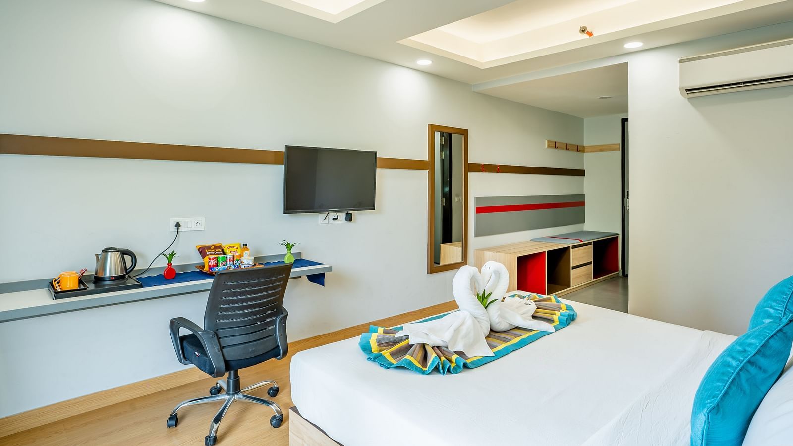 An image of a room where a chair there is a chair, a table, and a flat TV screen | Inde Hotel Golf Course Extension