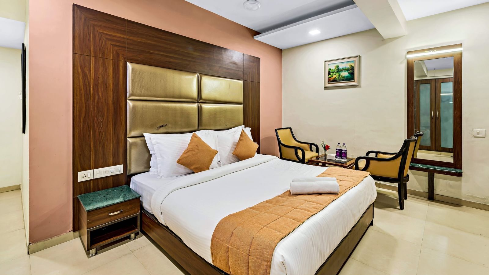 A well-lit executive room in Krushnai Resort featuring a double bed with white lnen and yellow runner.