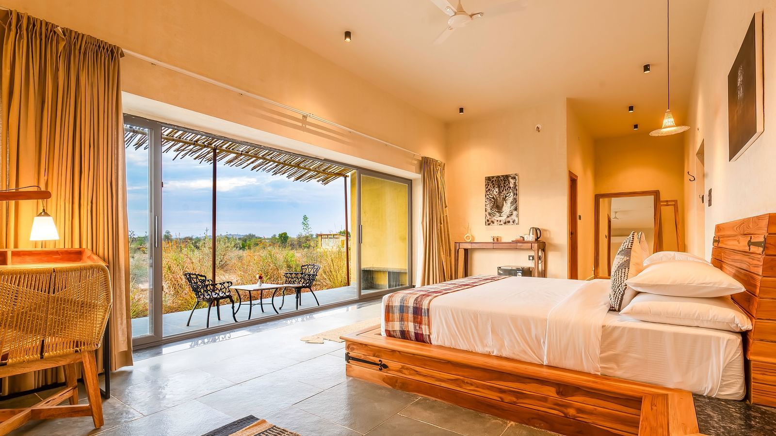 An image of bedroom at Kurja Jawai featuring a double size bed, a work desk and chair, a table with tea and coffee maker, and a coutryard with seating area 
