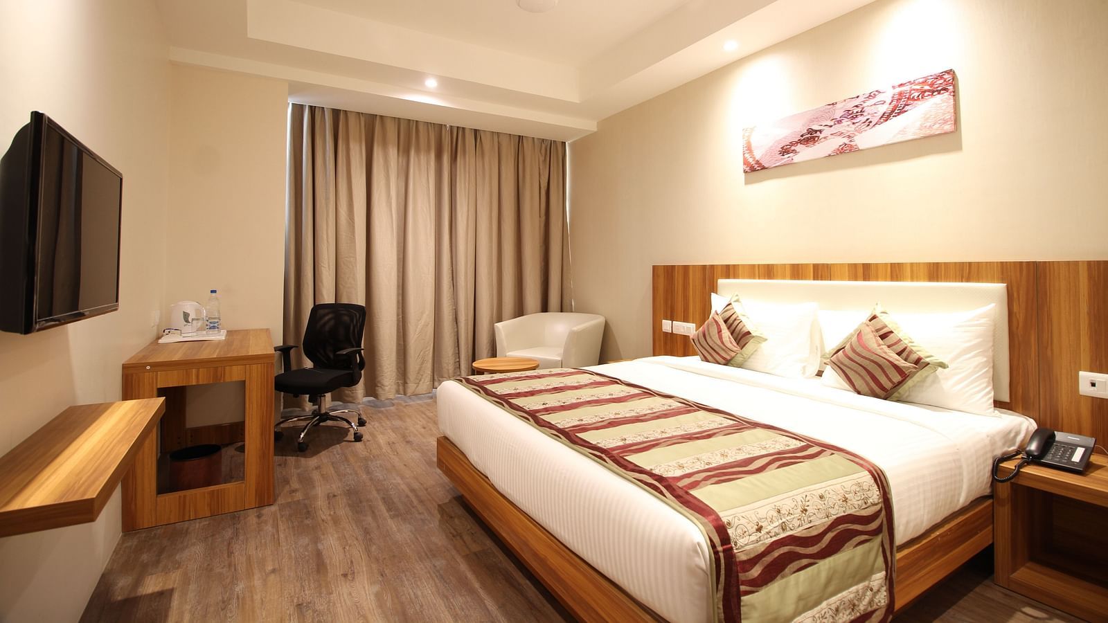 Corporate room with a posh bed and warm lighting captured from different angles while showcasing the in-2room amenities - the Le Roi Raipur Hotel
