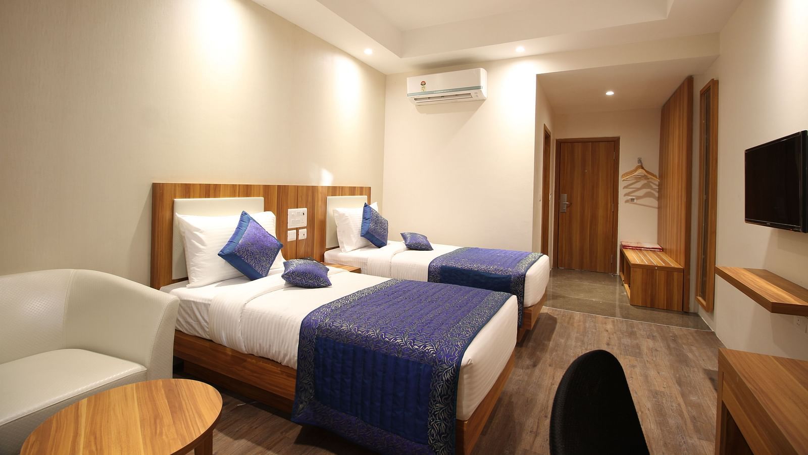 deluxe room with twin beds captured from different angles that showcase the in-room amenities and interior of the bedroom - le roi raipur hotel1