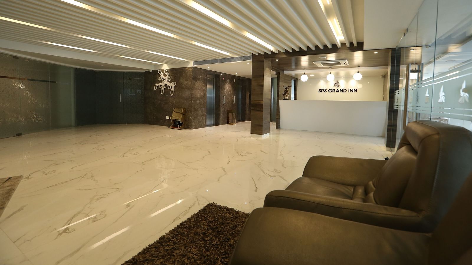 A hotel lobby with modern seating, a polished floor, and decorative ceiling lights - TGI SPS Grand, Coimbatore