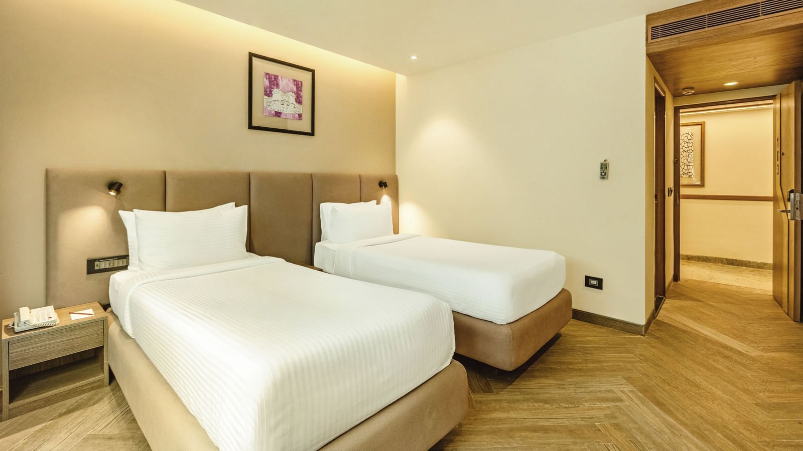A twin-bedded room with a television and a desk, seen from an angle, at Mango Hill Central, Chennai.