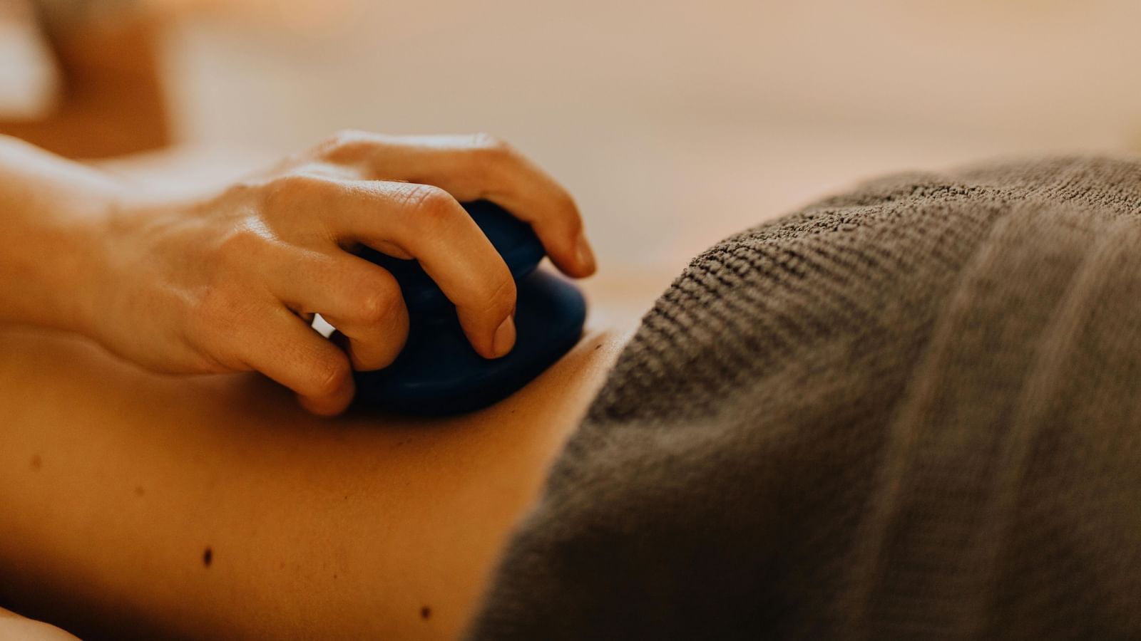 A therapist using a massage tool on a patient's back for deep tissue therapy.