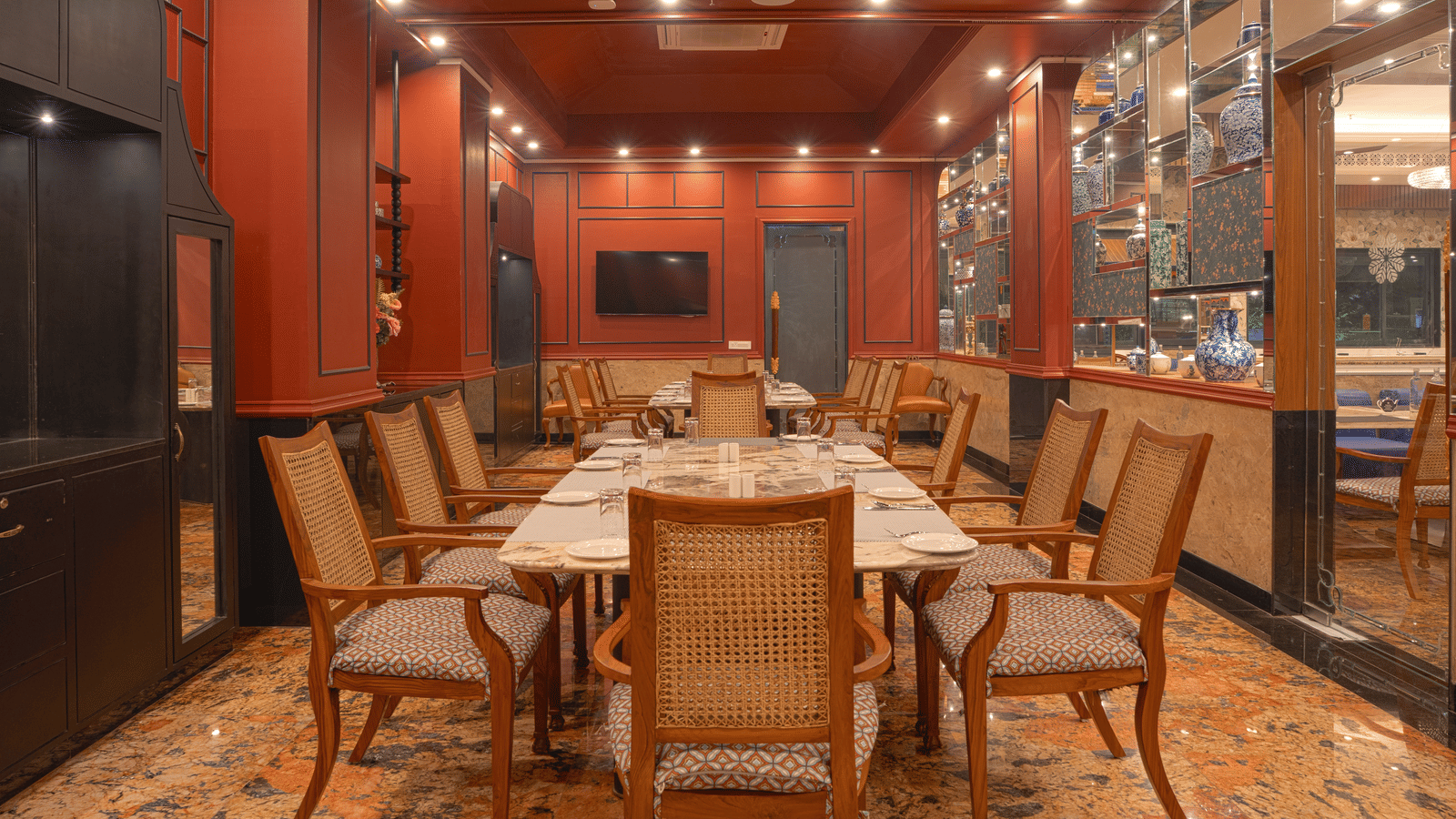 A dining room with a long wooden table set for a meal, surrounded by upholstered chairs and wood-panelled walls at MAYFAIR Bay Resort, Paradeep.