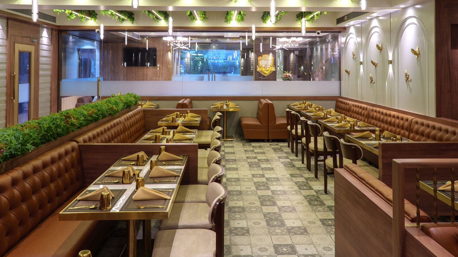 A spacious restaurant with numerous wooden tables and chairs, featuring bright overhead lighting and some greenery - Melior Inn