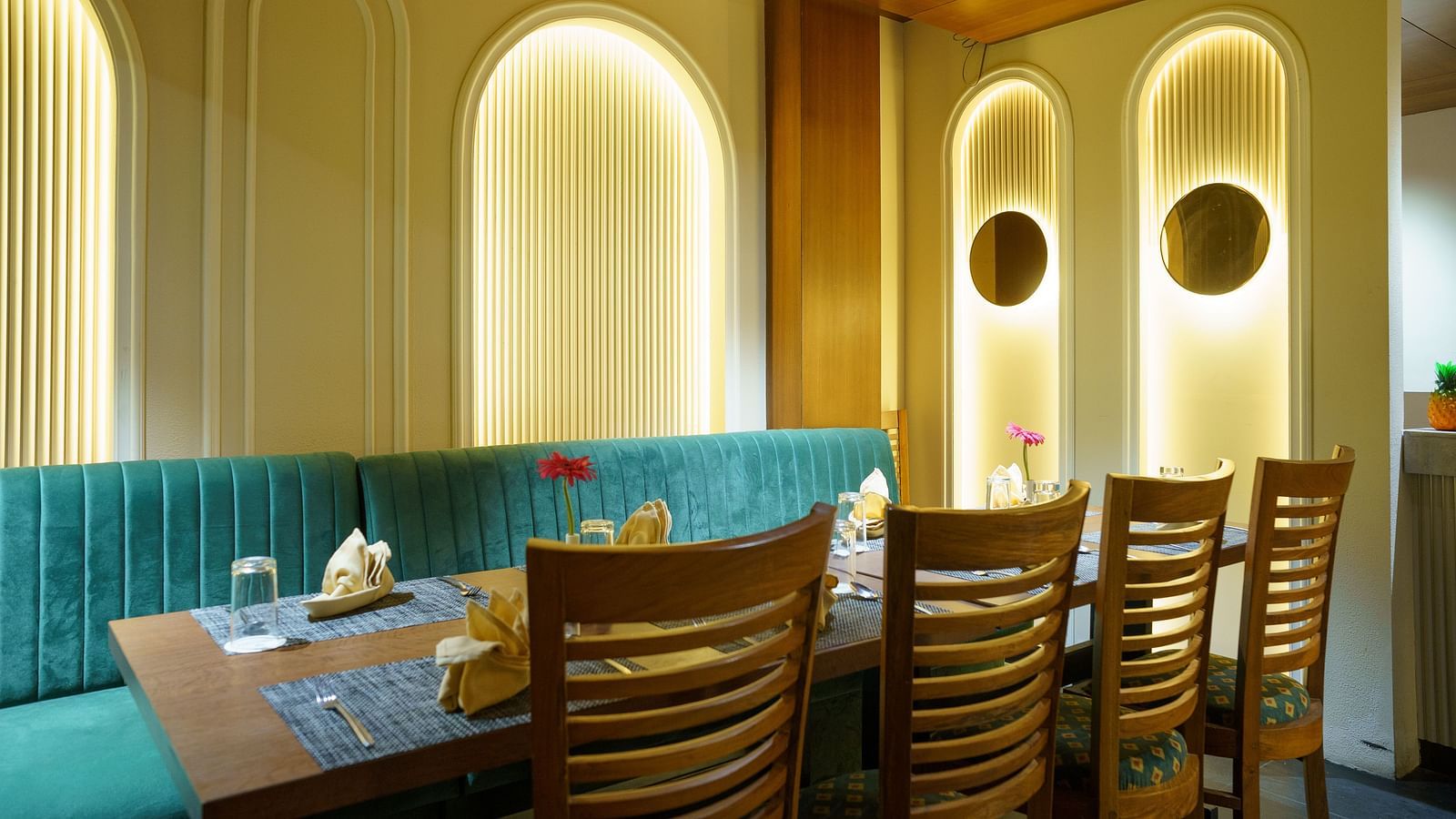 A wide shot of a dining area with booths featuring turquoise upholstery and wooden tables at Orsino Spa Resort.