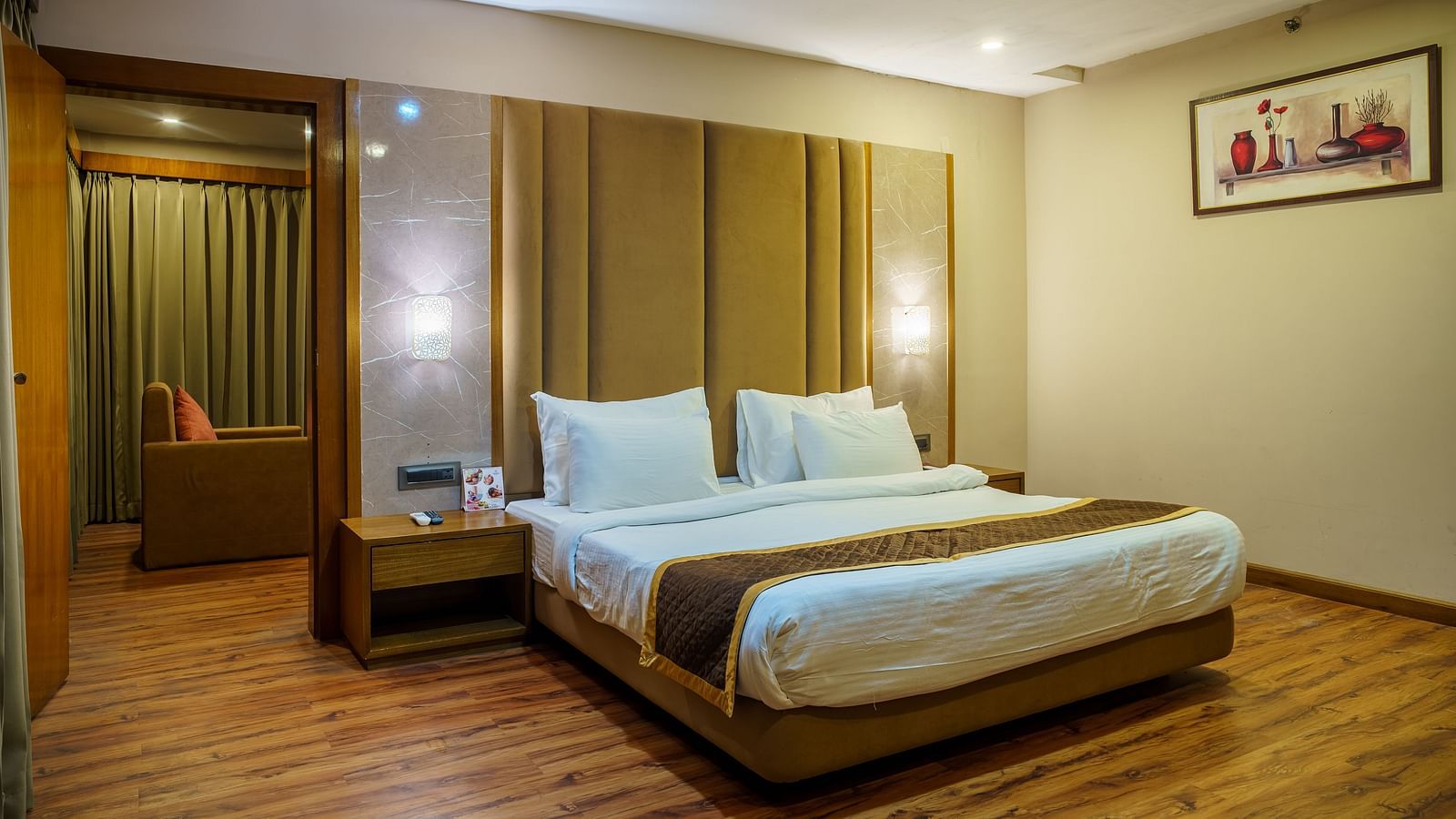 A room at Orsino Spa Resort with a bed featuring a light-coloured headboard, a bedside table, and wooden accents.