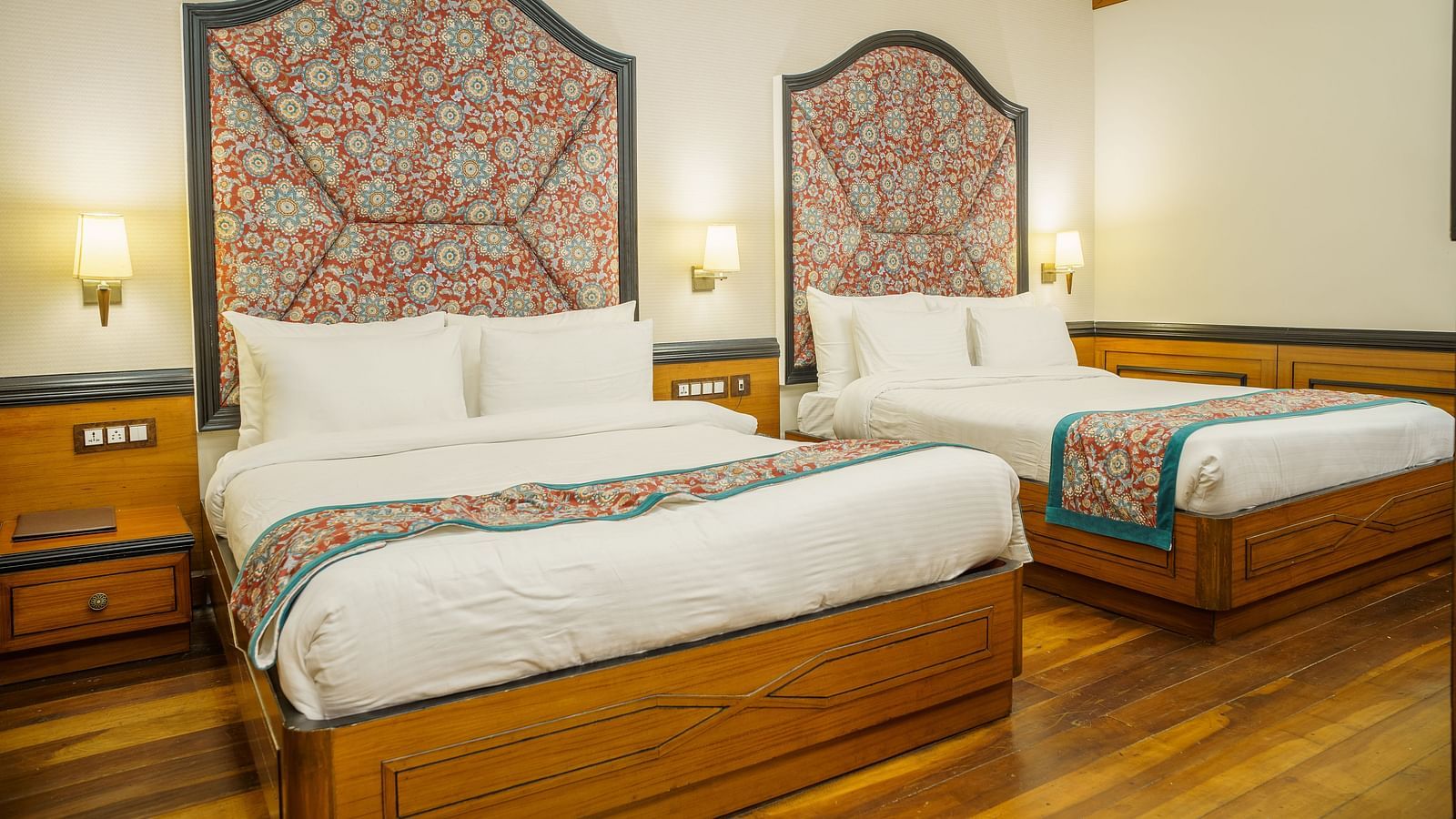A room at Orsino Spa Resort with two beds, each with a distinctive patterned headboard and a colourful throw.