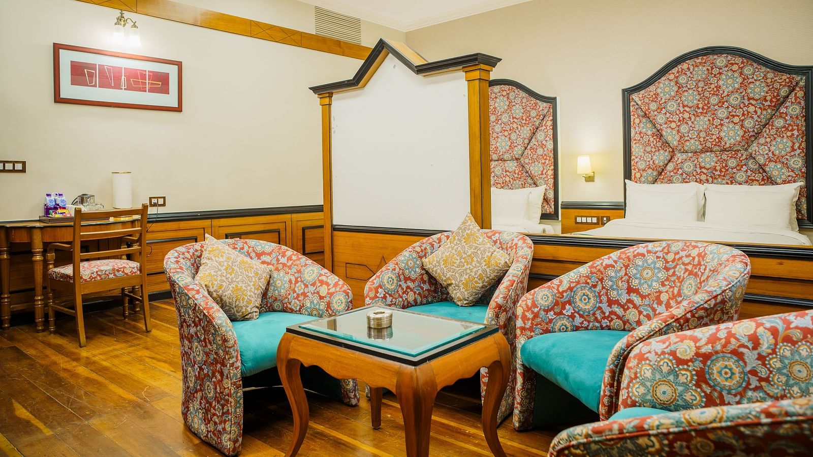 A seating area at Orsino Spa Resort with several armchairs and a sofa, all with patterned upholstery, and wooden wall panelling.