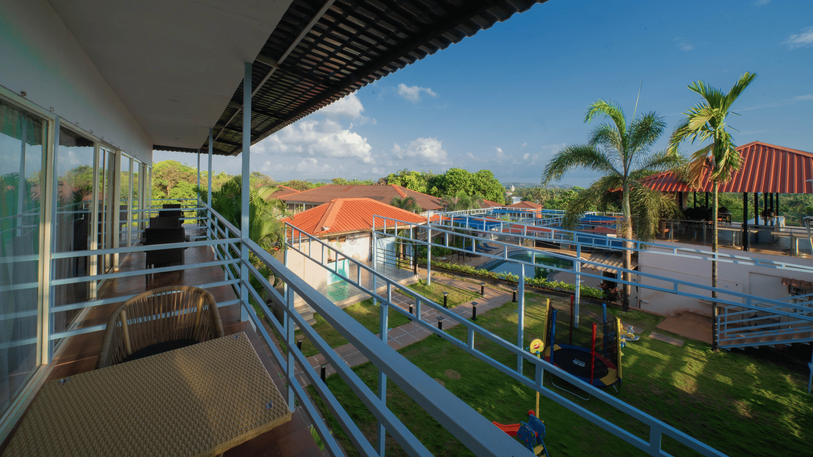 Our resort’s orange-tiled buildings surrounded by lush greenery and coconut trees, captured beautifully from a high-floor balcony - Perfectstayz Koko Maya