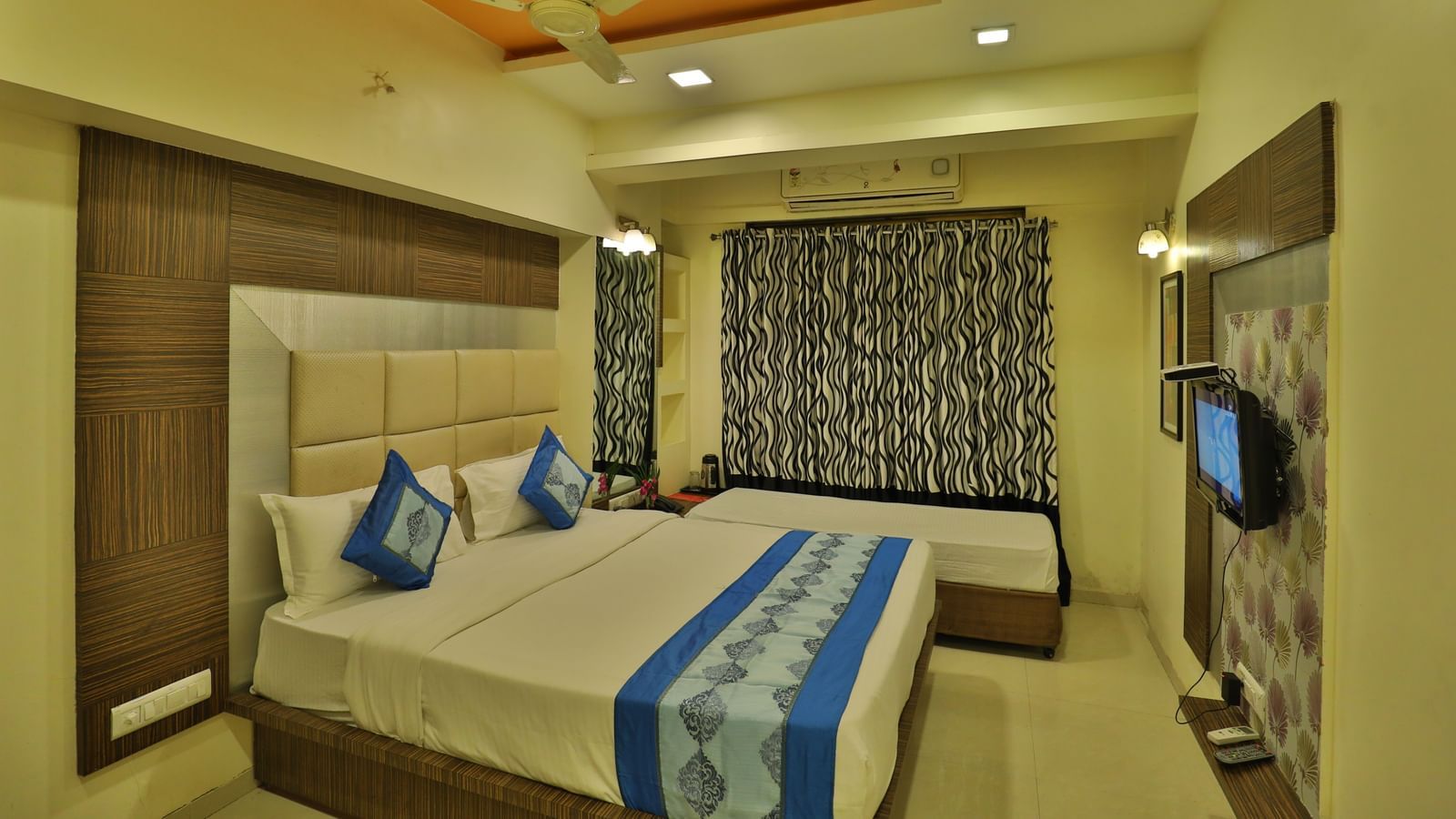 A cosy hotel room with a large bed, side tables, a television, and ample natural light - Retreat Heritage, Lonavala
