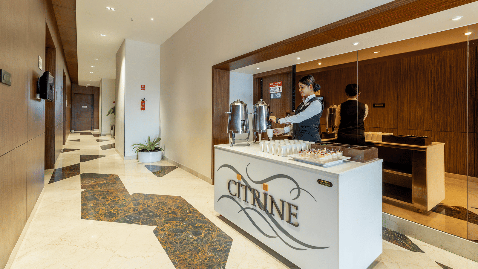 The reception counter at the Citrine Hotel, with the hotel logo and a person standing behind the desk.
